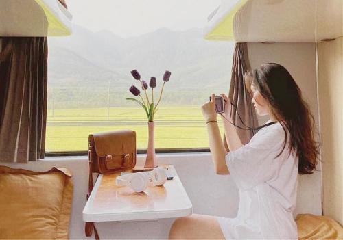 Ảnh du khách nhìn ra cửa sổ tàu hỏa ngắm cảnh